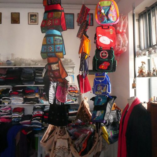 This is an image of inside the YMCA Charity & Vintage Shop. It shows an installation of various bags and backpacks strung from the ceiling.