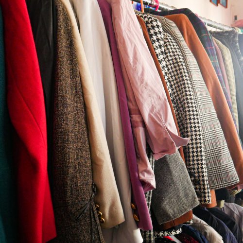 This is an image of inside the YMCA Charity & Vintage Shop. It shows racks of women's jackets.